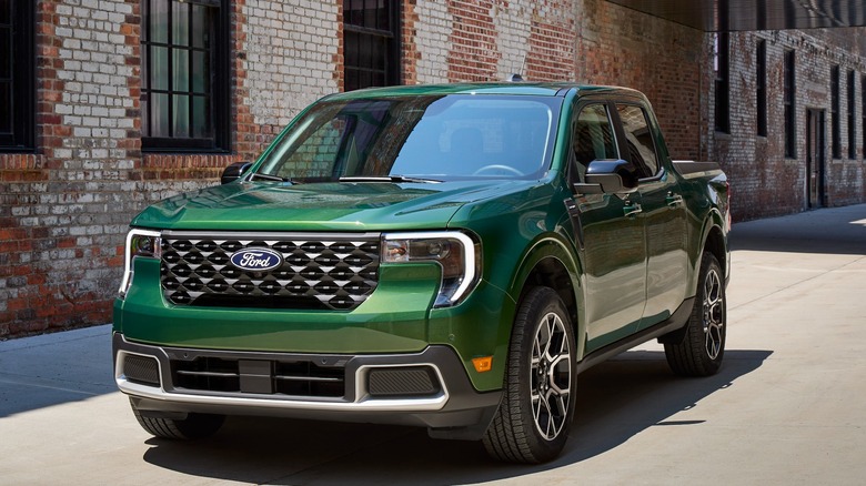 A forest green Ford Maverick in front of a brick wall with windows