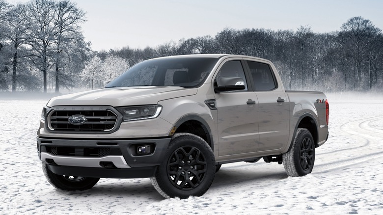 A gray Ford Ranger in snow with trees in the background