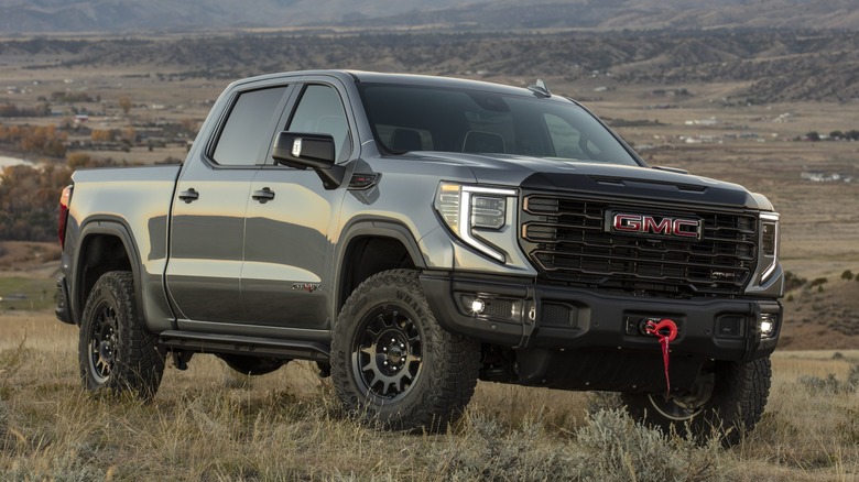 A front three-quarter view of an olive green GMC Sierra 1500 on dirt