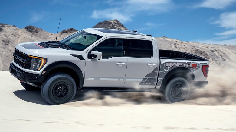 A silver Ford F-150 Raptor R kicking up sand in the dunes