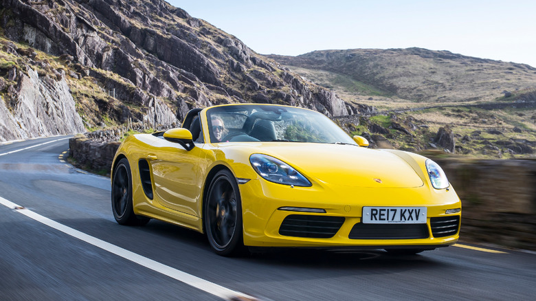 The Porsche 718 Boxster S driving, yellow exterior, front 3/4 view