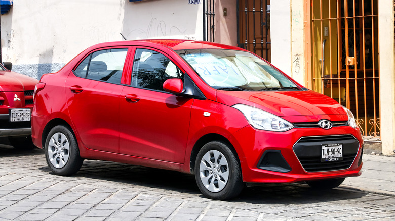 A red Hyundai i10 on a city street