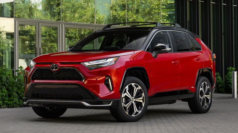 Red 2025 Toyota RAV4 Plug-in Hybrid parked in front of building