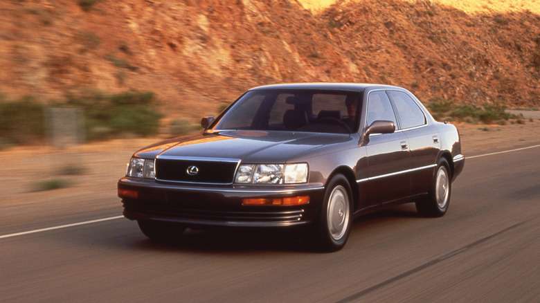 First-gen 1993 Lexus LS 400 driving at speed on an open road front 3/4 view