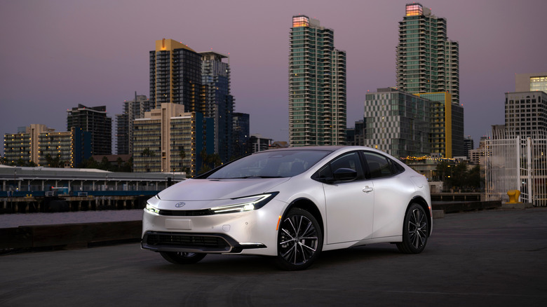 White 2024 Toyota Prius front 3/4 view in front of skyscrapers 