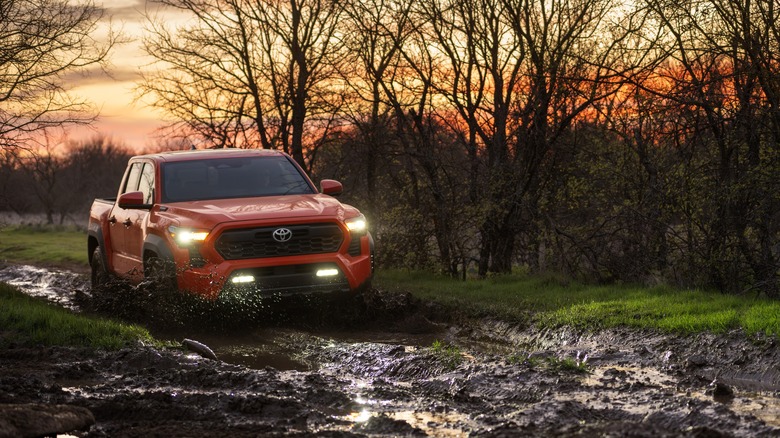 Red 2024 Toyota Tacoma i-FORCE MAX driving through mud