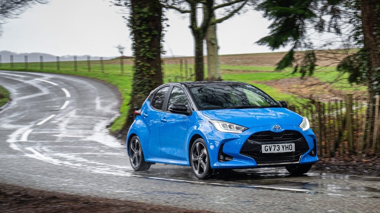 Blue 2024 Toyota Yaris front 3/4 view driving on a wet twisty road