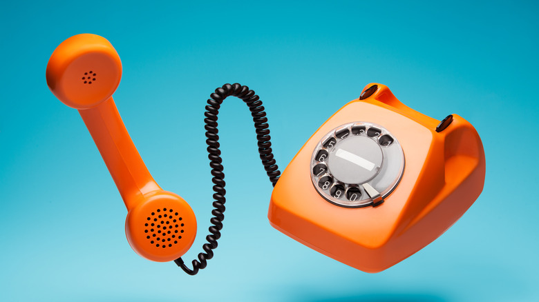 Orange rotary corded telephone with blue background