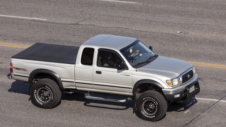 A silver first generation Toyota Tacoma on the move, side aerial view