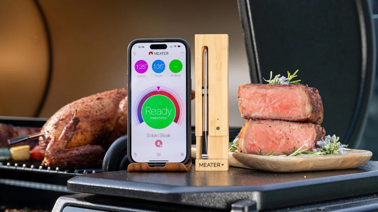 A Meater thermometer on a grill next to food