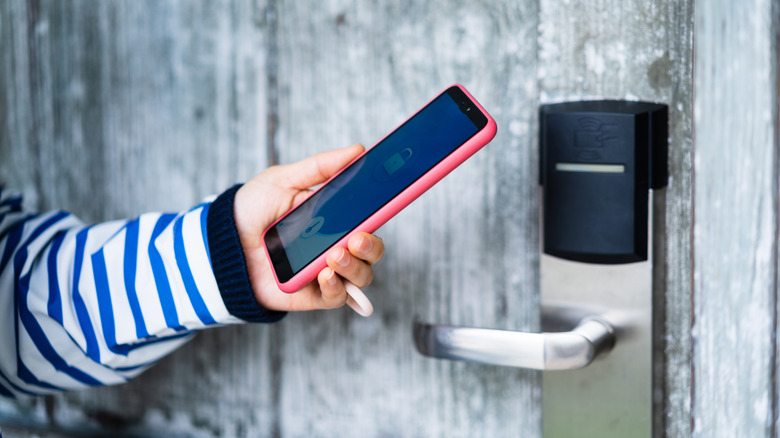 A person using a smartphone to unlock a fence latch