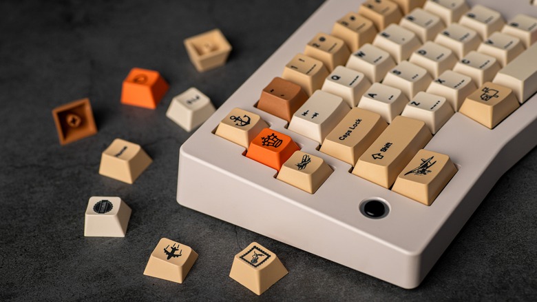 A mechanical keyboard sitting next to spare key caps