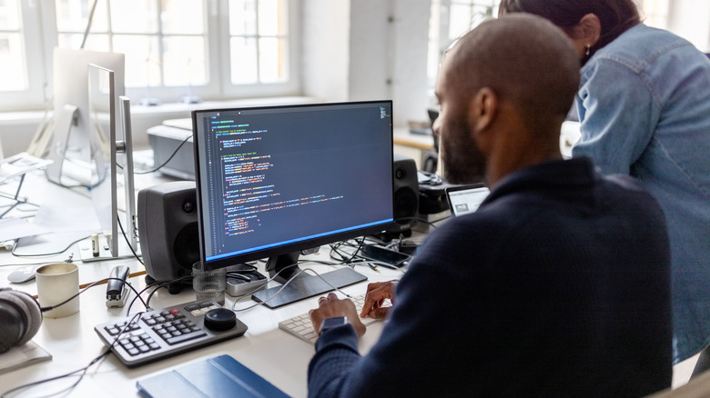 A man working on computer code in a white office