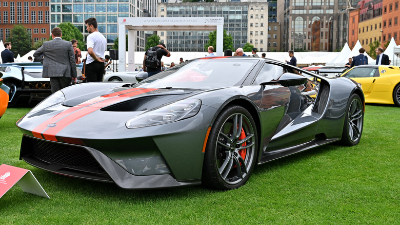 The Ford GT at an auto show, gray with orange stripes, front 3/4 view