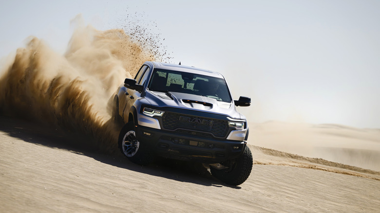 The RAM 1500 RHO kicking up some sand, silver exterior, front 3/4 view