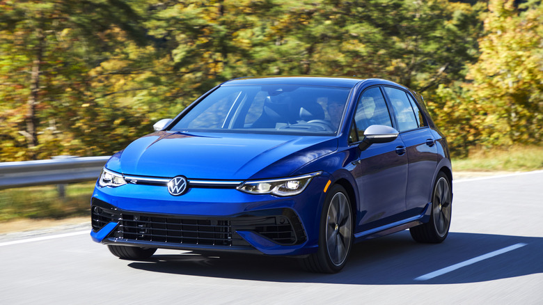 The 2024 Volkswagen Golf R in blue driving, front 3/4 view