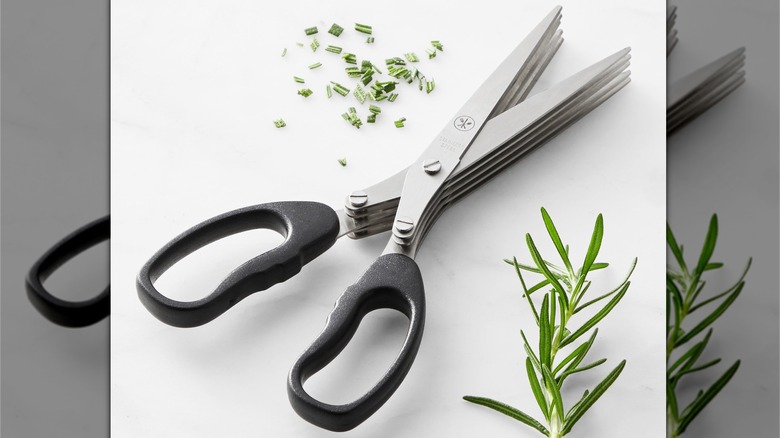 A pair of herb scissors next to some rosemerry