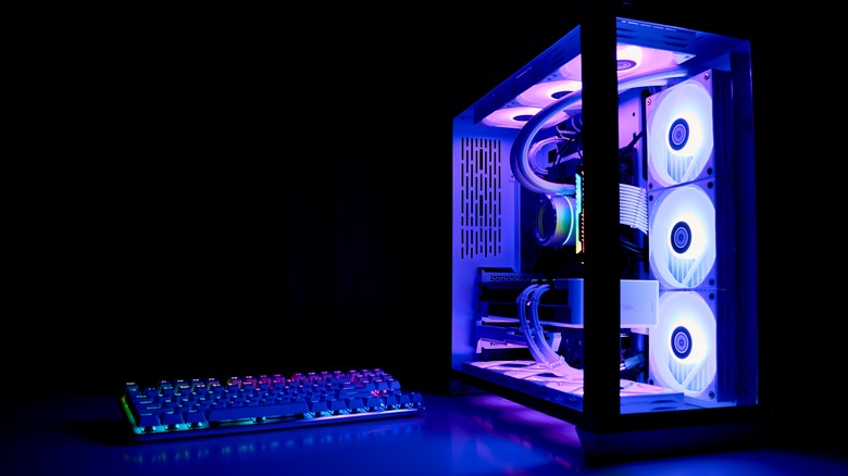 A PC tower with RGB lighting next to a computer keyboard