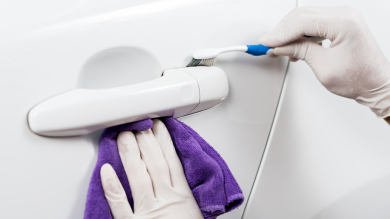 Driver cleaning door handle with toothbrush