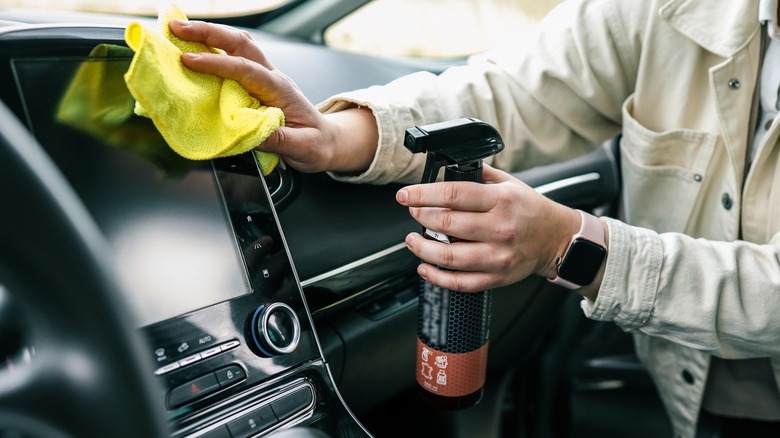 Driver cleaning car navigation screen with towel