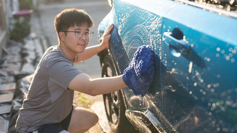 Young man washing a blue car