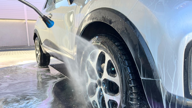 Rinsing car rear tire with pressure washer