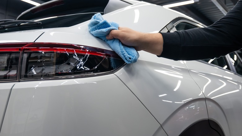 Driver using microfiber towel to clean rear headlight