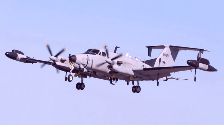 RC-12 Guardrail flying over blue skies with landing gear down