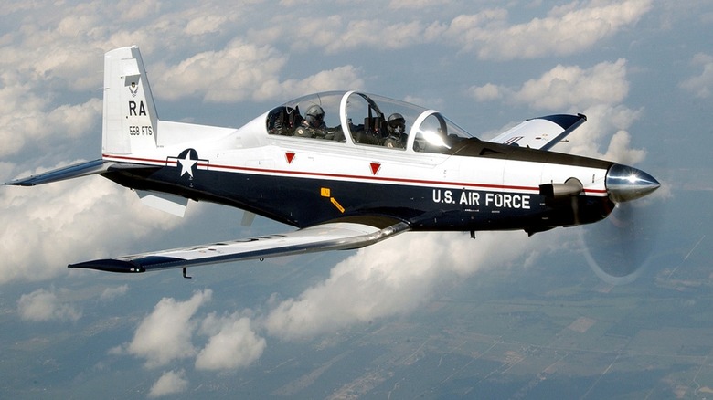 T-6 Texan II with a pilot and student pilot flying over cloudy skies