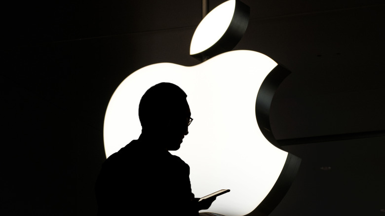 Steve Jobs looking at iphone in front of apple logo