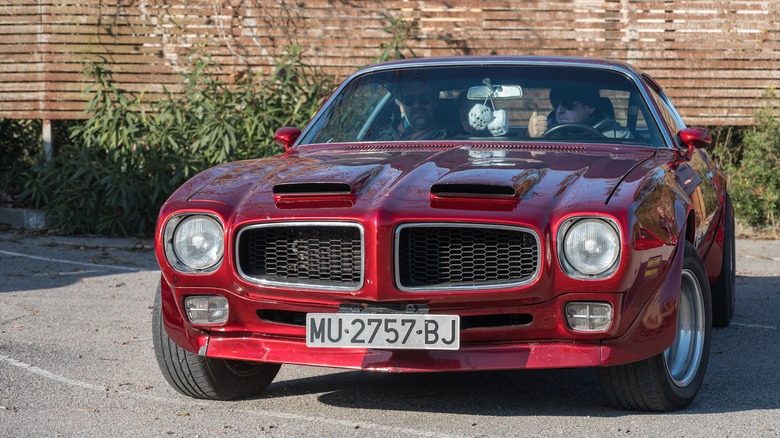 People inside red Pontiac Firebird