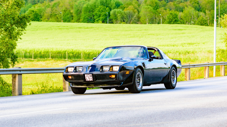 Black Pontiac Firebird driving down road