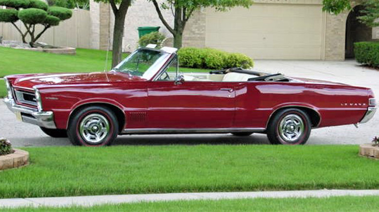 A red Pontiac LeMans convertible parked in a suburb