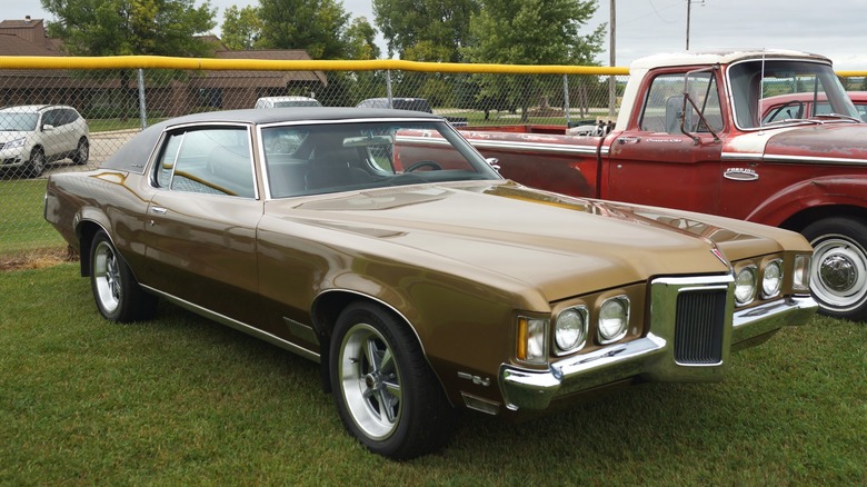 Bronze 1970 Pontiac Grand Prix parked on grass