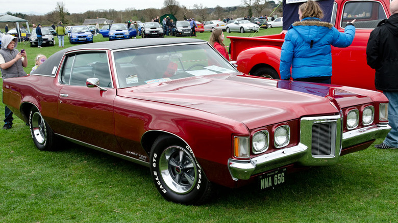 Red 1969 Pontiac Grand Prix parked on grass