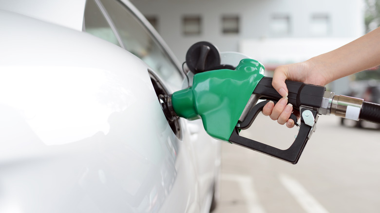 Hand pumping gas into car