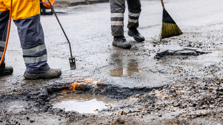 Maintenance workers fixing potholes in road