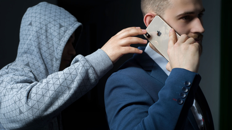 Hooded man grabbing person's iPhone