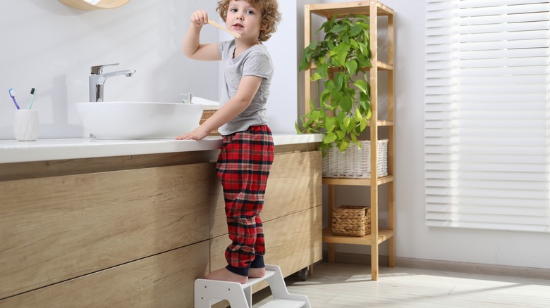 child using step stool to brush teeth
