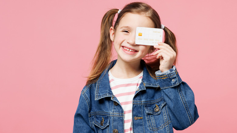 Young girl holding a credit card over one eye