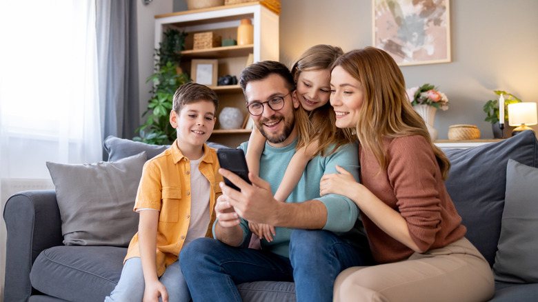 Family of four grouped around a smartphone