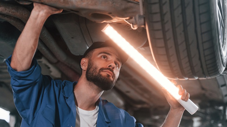 man working on car holding light