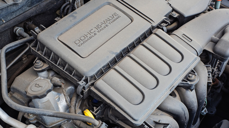 Dusty dual overhead camshaft car engine in an engine bay