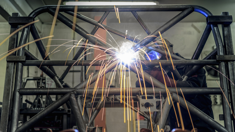 Welder at work fabricating a roll cage