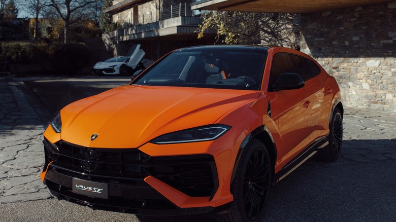 Orange Lamborghini Urus SE parked in front of a house