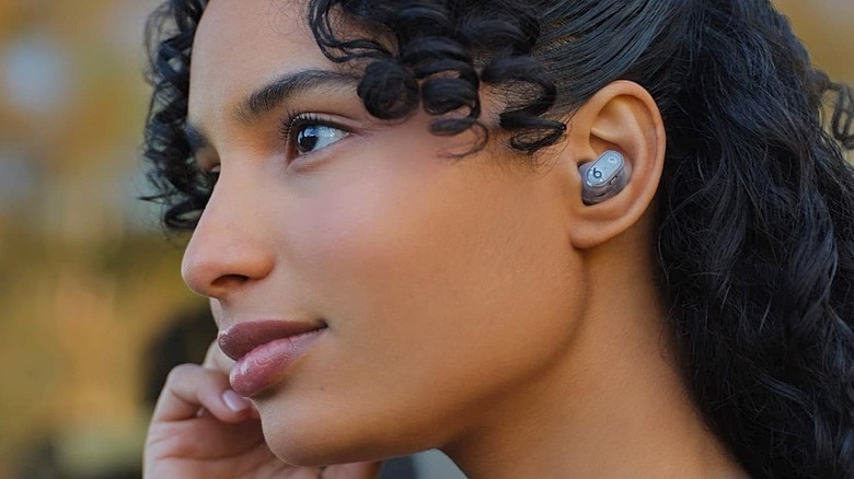 A woman wearing the Beats Studio Buds+ ANC earbuds.