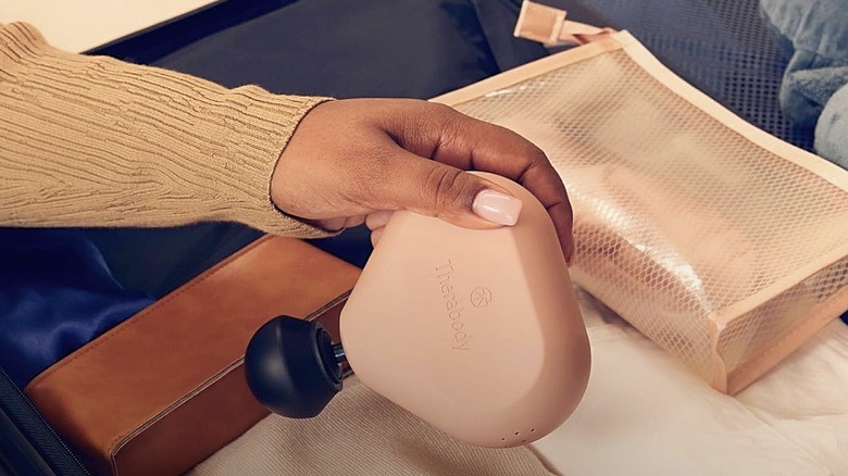 A woman packing the TheraGun Mini Massage Gun into her luggage.