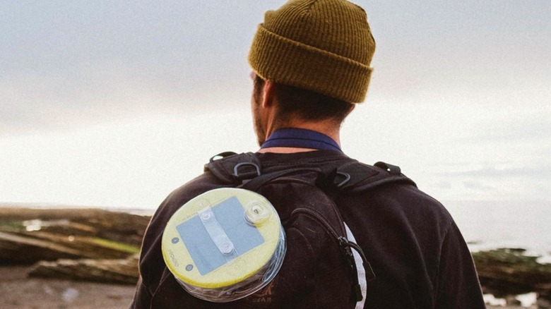 A hiker straps the MPOWERD Luci Pro Outdoor 2.0 to his backpack to charge.