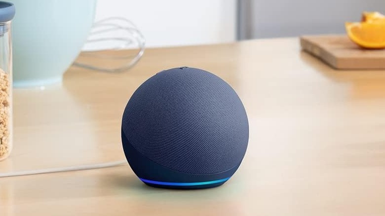 Black round electronic speaker with illuminated blue ring around the top