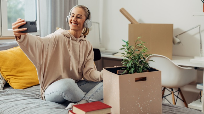 Young woman taking a selfie while surrounded by moving boxes